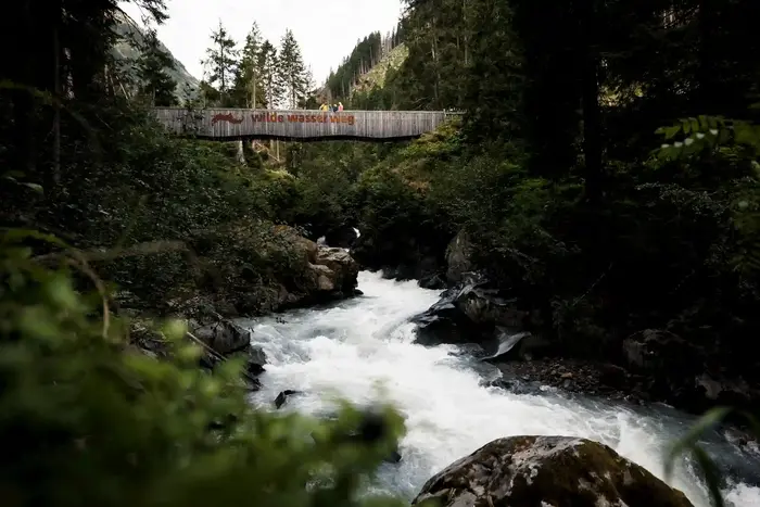 Suspension bridge marked WildeWasserWeg above the rushing mountain stream