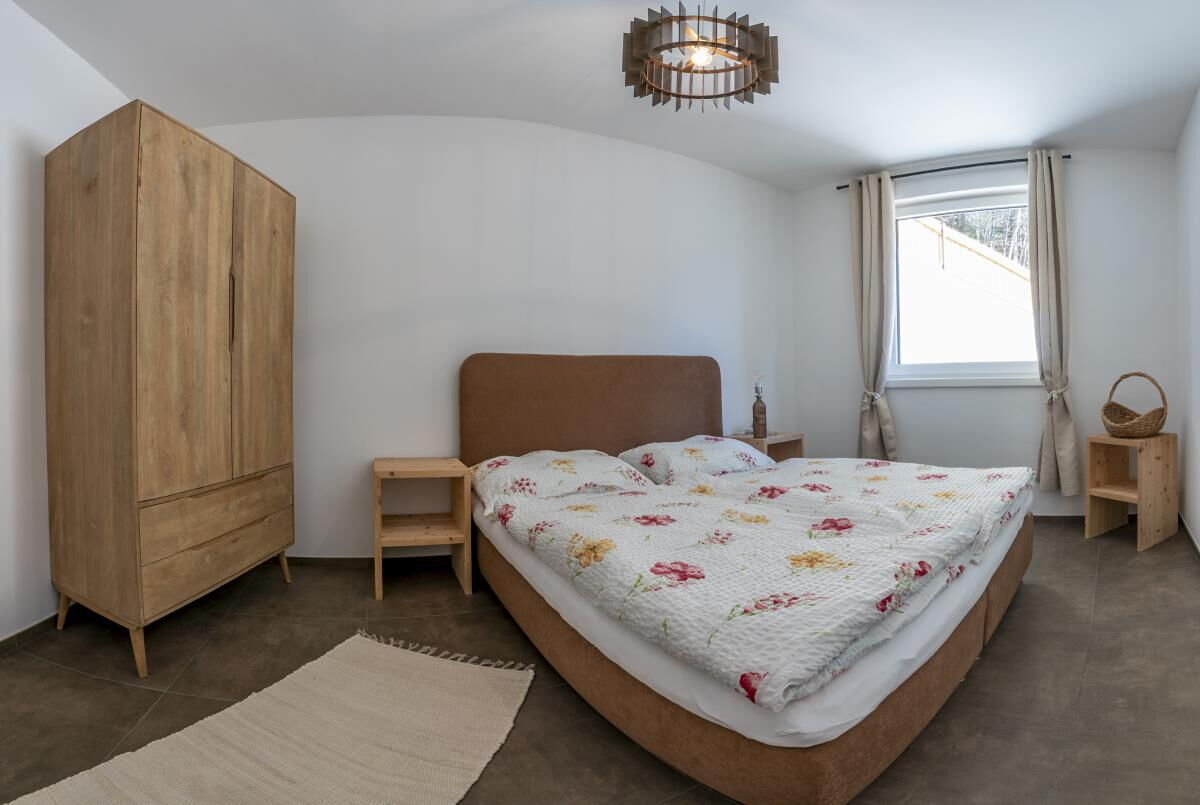 Bedroom with double bed and light wooden wardrobe in the Alpenfamilienglück in Gnadenwald, one of two bedrooms