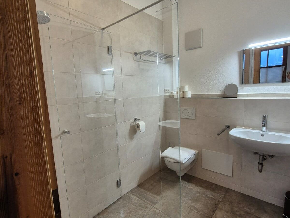 Badezimmer mit bodengleicher Glasdusche, Waschbecken und WC in der Roggnkammer am Riedhof in Breitenbach in Tirol