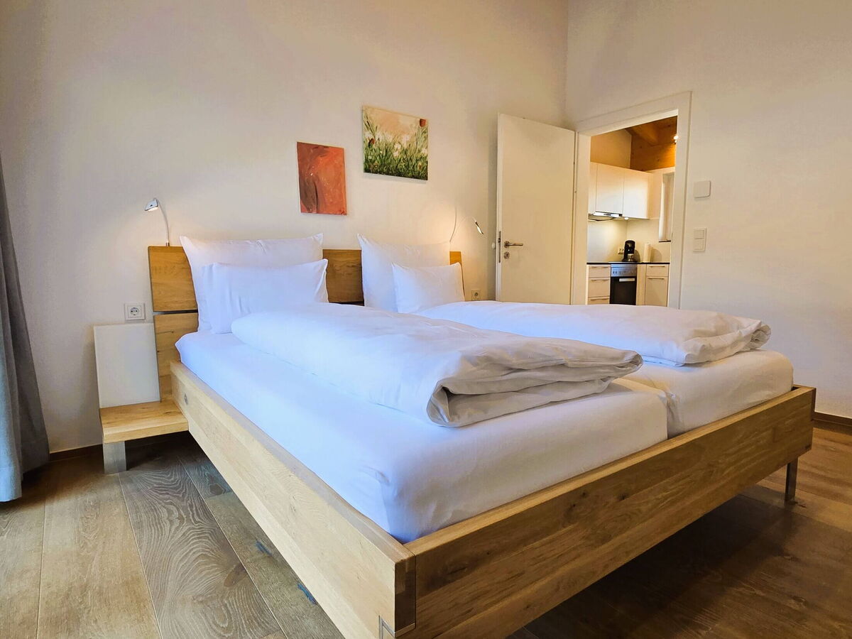 Bedroom with double bed and an open passage through to the kitchen in the Panorama luxury lodge Ifen, loft apartment in the Kleinwalsertal