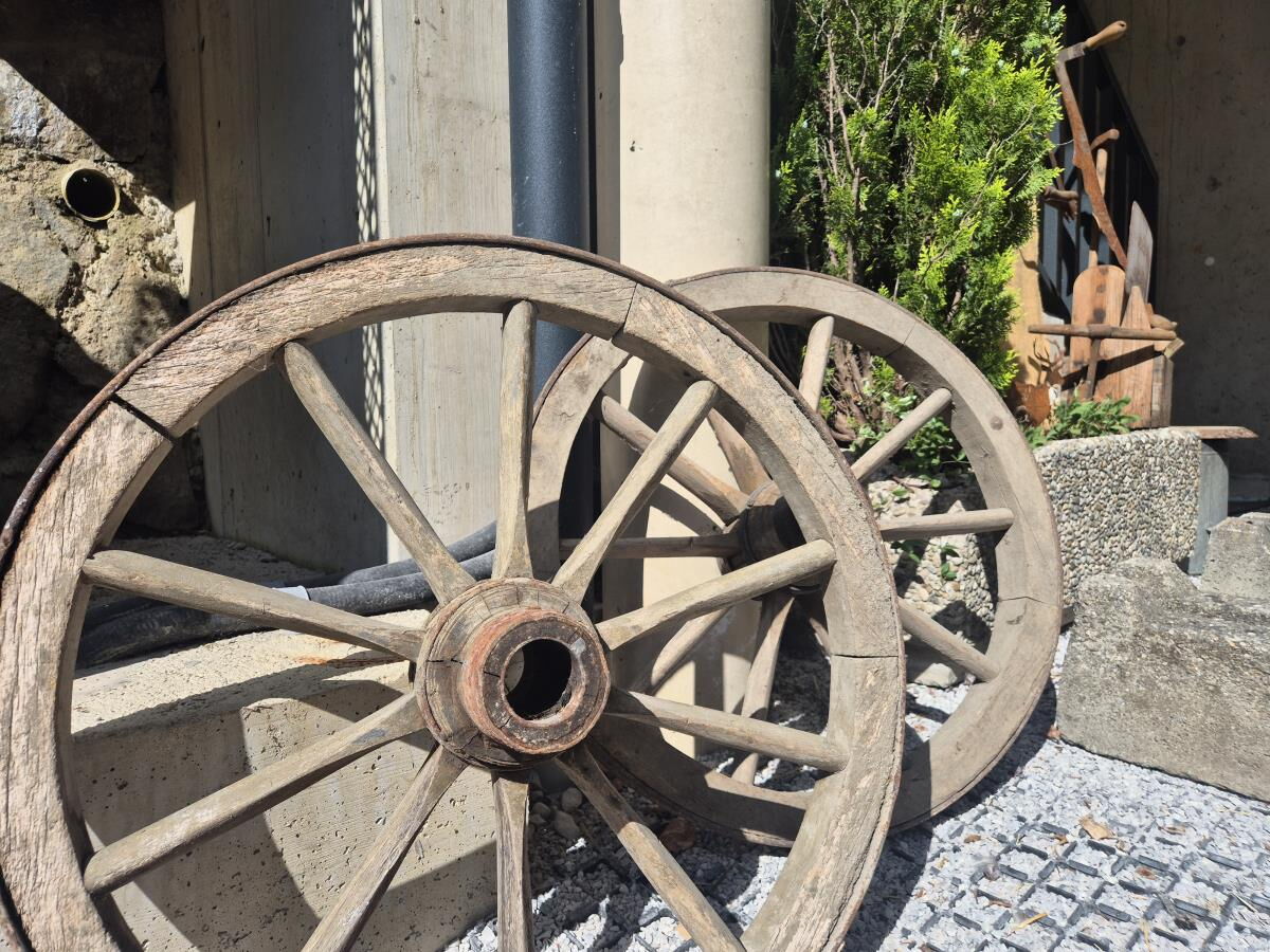 Zwei alte hölzerne Wagenräder lehnen an der Hauswand am Pulvererhof in Gnadenwald in Tirol