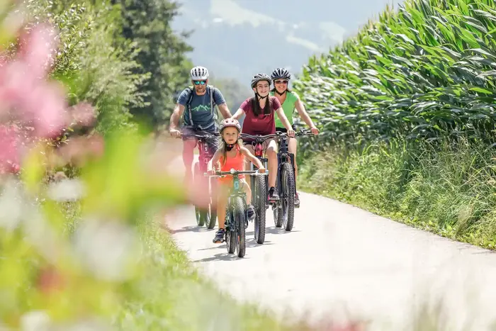 Family cycling on the Zillertal cycle path through meadows in the valley