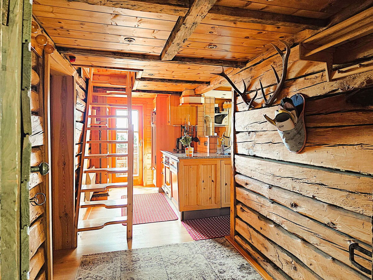Blick vom holzverkleideten Vorhaus der Pietschacher Almhütte durch die offene Tür in die Küche