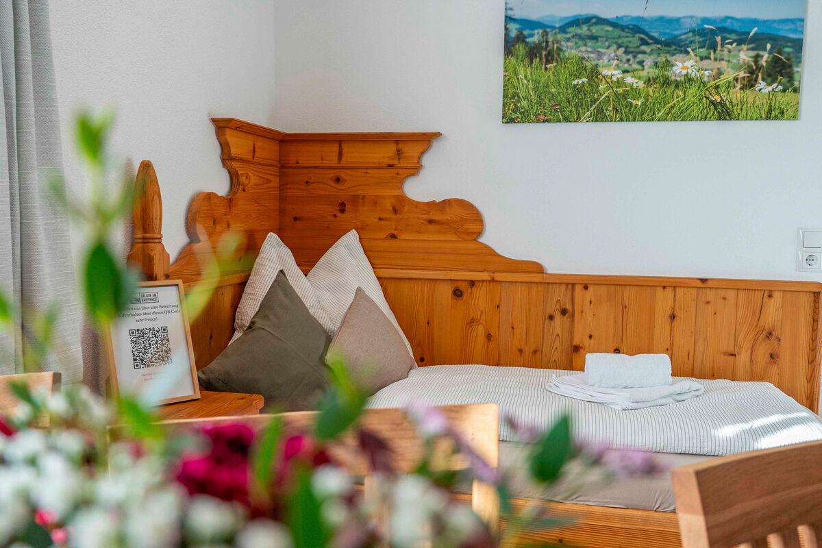 Schlafzimmer im Zuahaus mit Altholz-Kopfteil und Blumen, Ferienwohnung am Bauernhof in Tirol