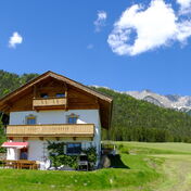 Das Grafenhäusl am Naturpark Karwendel in Tirol, Holzhaus mit Balkon auf der Wiese vor dem Karwendelgebirge, Ferienhaus in ruhiger Lage