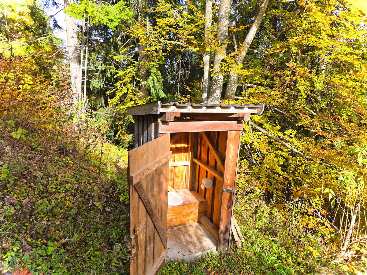 Traditionelles Plumpsklo aus Holz neben der Abenteurer-Hütte mit Blick ins Tal, Niederösterreich.