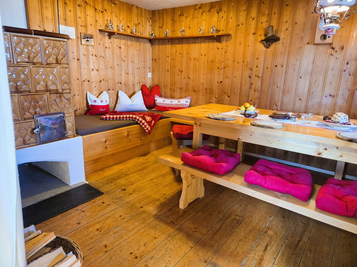 Dining table and tiled stove from the other side in the Breitbergalm, mountain cabin for 10 people on the Fügenberg