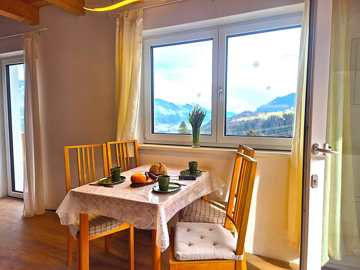 Heller Essplatz mit Holztisch und Stühlen am Fenster mit Blick ins Inntal in der Ferienwohnung Sternenhimmel am Kolsassberg, Platz für bis zu fünf Personen