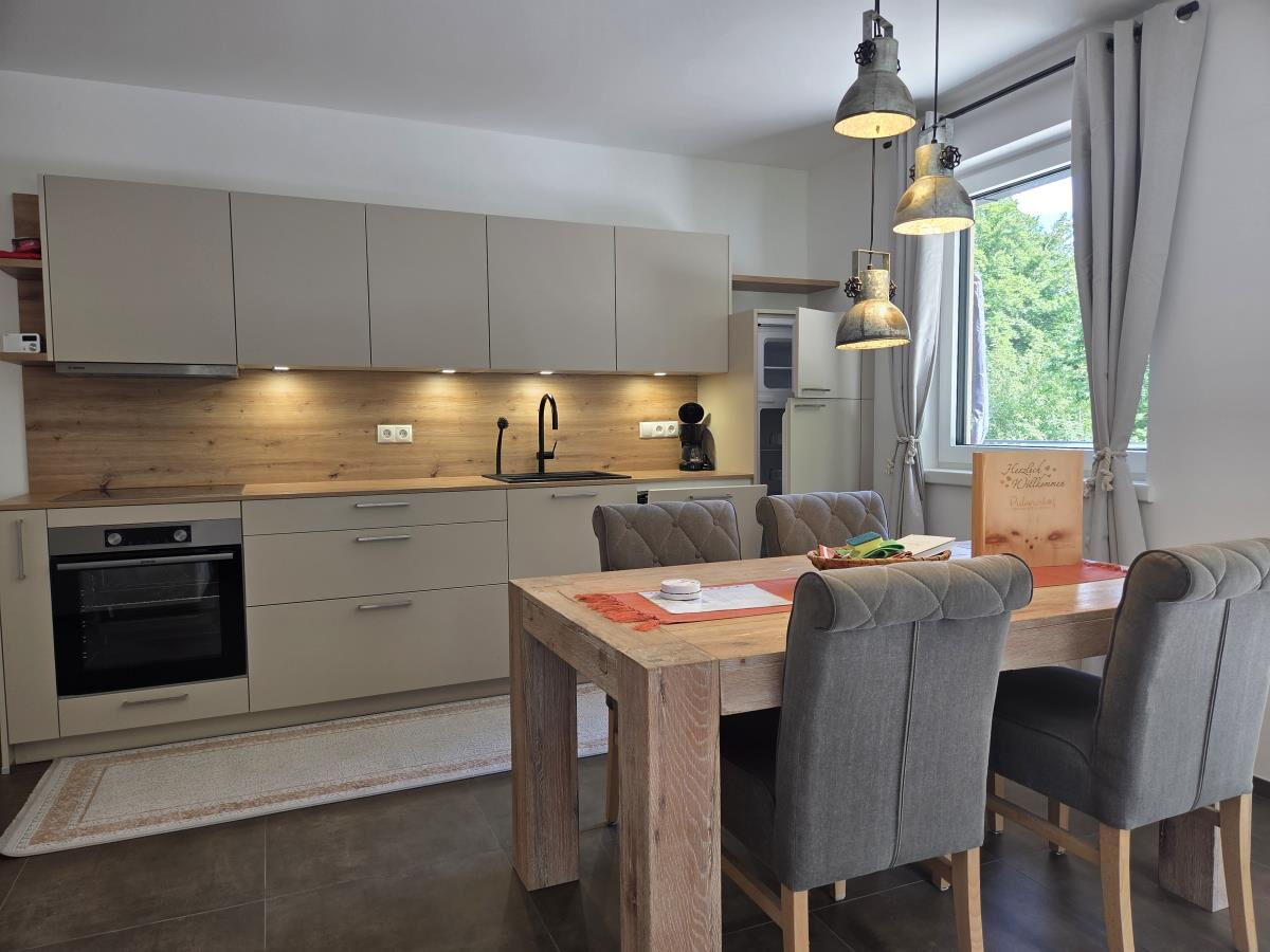 Bright kitchen of the Waldsicht holiday apartment with oven, hob and a large dining table with six chairs