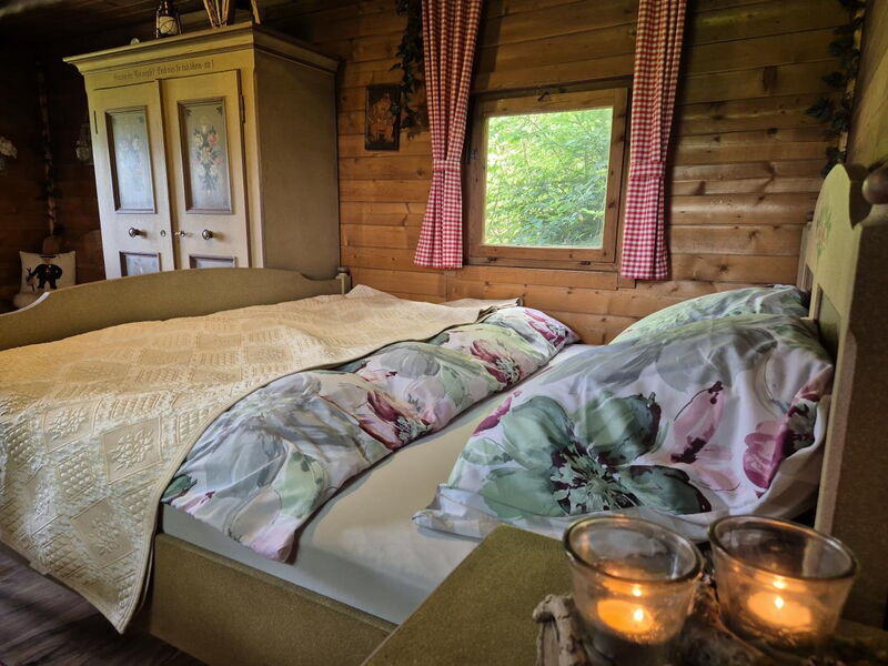 Bett mit Rosenmuster und Teelichtern im Waldhüttl am Karwendel