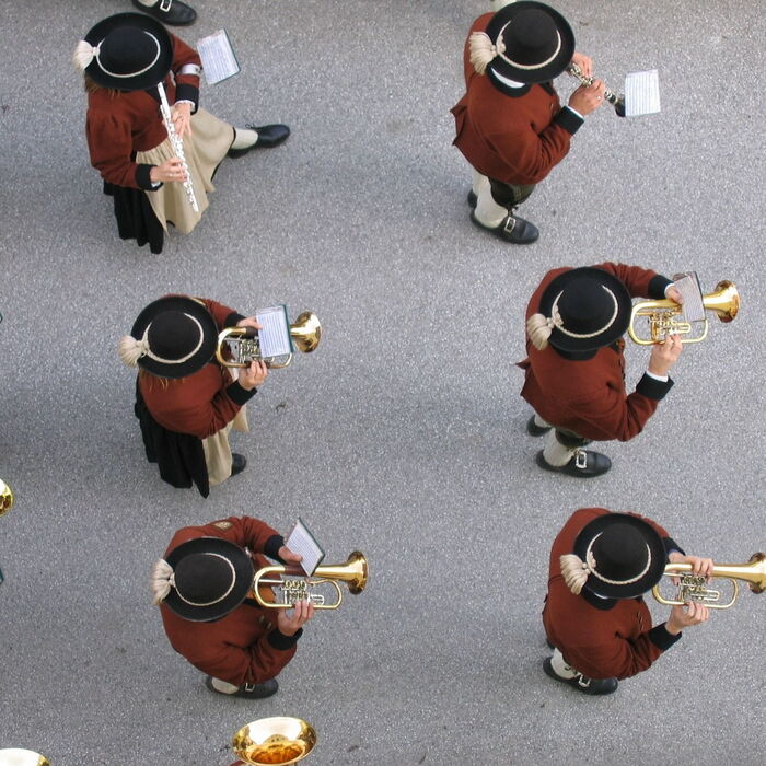 Traditioneller Aufmarsch der Musikkapelle: Uniformierte Musiker marschieren in festlicher Tracht durch die Straßen, begleitet von zackiger Marschmusik und einer lebhaften Atmosphäre.