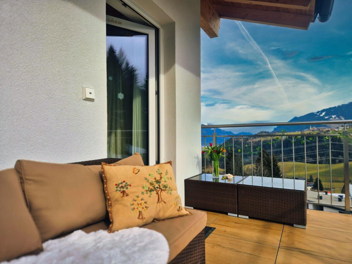 Gemütliche Sitzecke mit Sofa und Kissen vor der Panoramafensterfront in der Ferienwohnung Sternenhimmel am Kolsassberg, Blick auf die Berge und ins Inntal