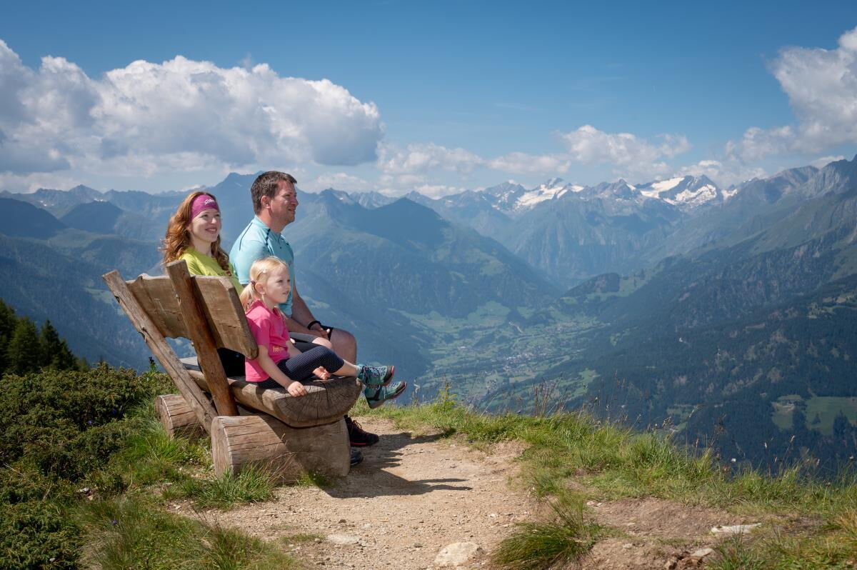 Familie auf einer Bank mit Blick über das Tal bei Matrei in Osttirol, Nationalpark Hohe Tauern