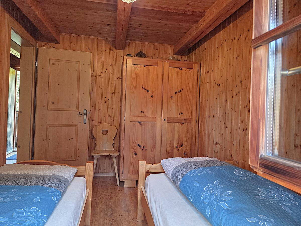 Zweites Schlafzimmer mit Betten und Holzstuhl in der Zarze Almhütte, Selbstversorgerhütte auf 1.880 m in Osttirol