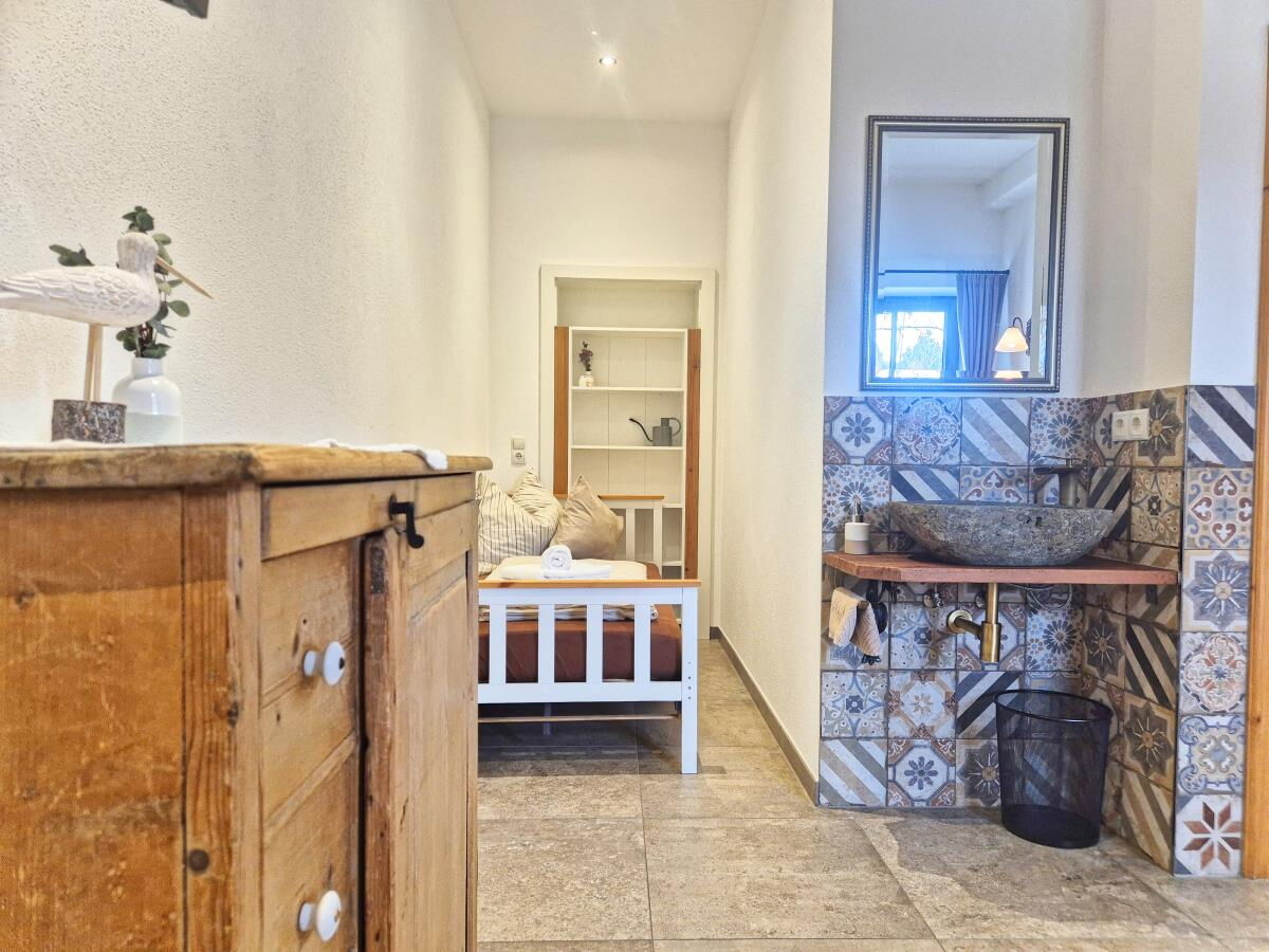 Flur mit Kommode und Bad mit Mosaikfliesen in d'Kloane Mühle, Ferienwohnung am Riedhof in Tirol