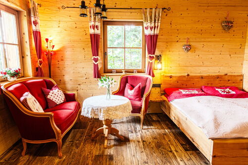Schlafbereich aus Zirbenholz und in rot erstrahlt die Couch und der Stuhl nebenan.