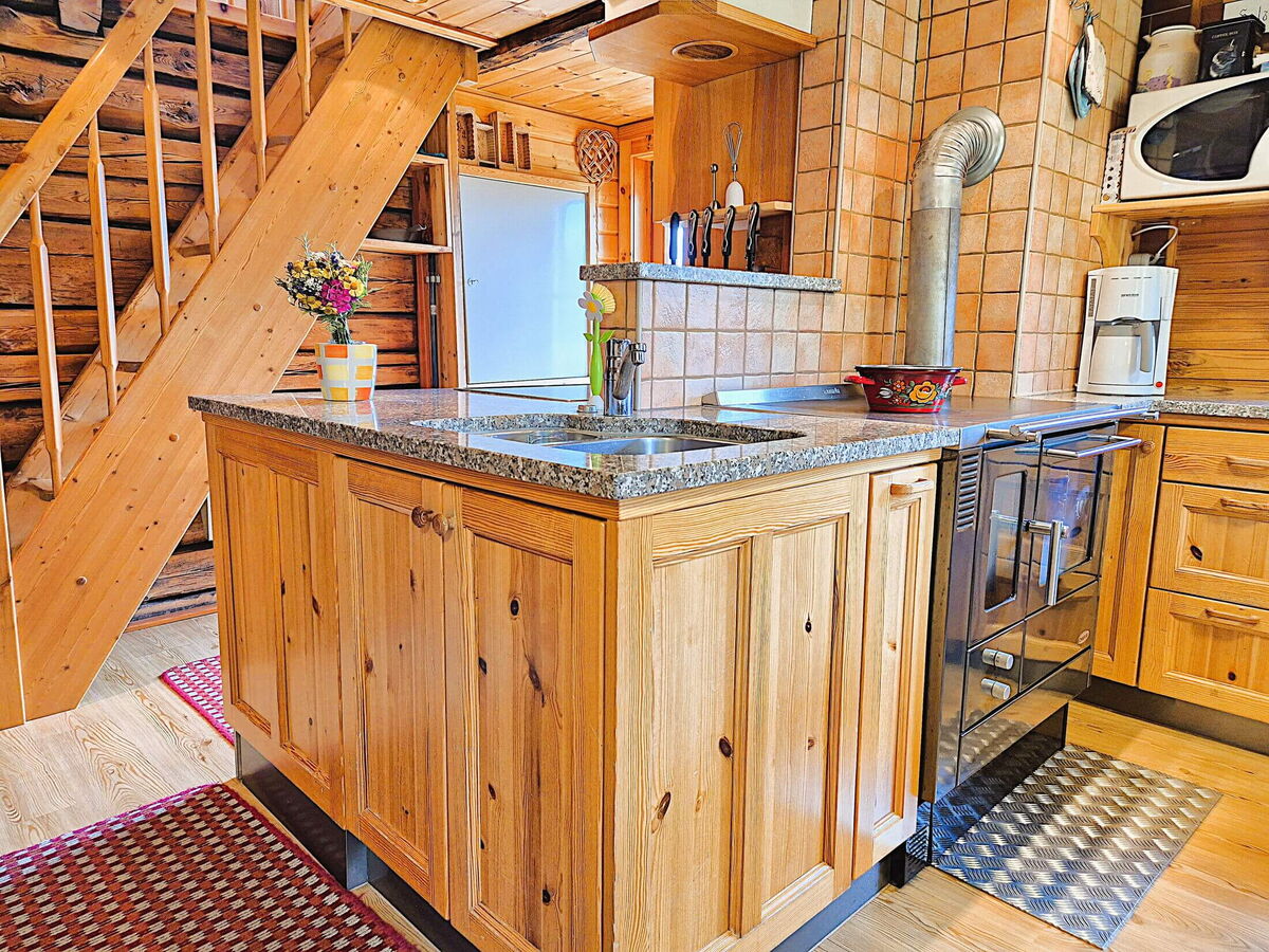 Kochinsel mit Steinplatte und alter Holzherd mit Ofenrohr in der Wohnküche der Pietschacher Almhütte