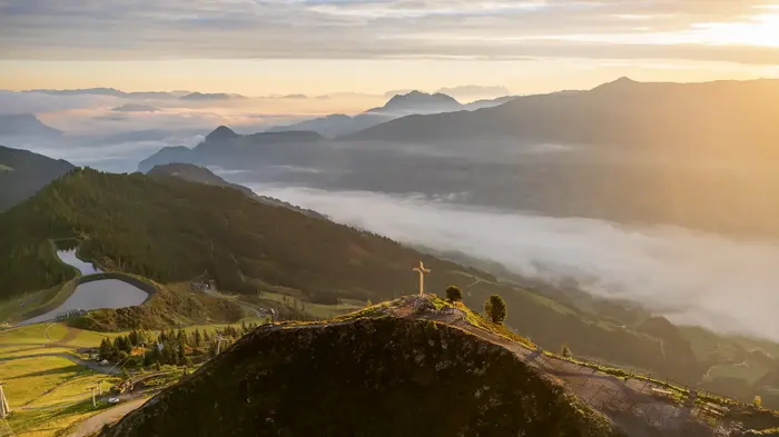 Hiker on the ridge above Fügen in the Zillertal, morning mist lies in the valley