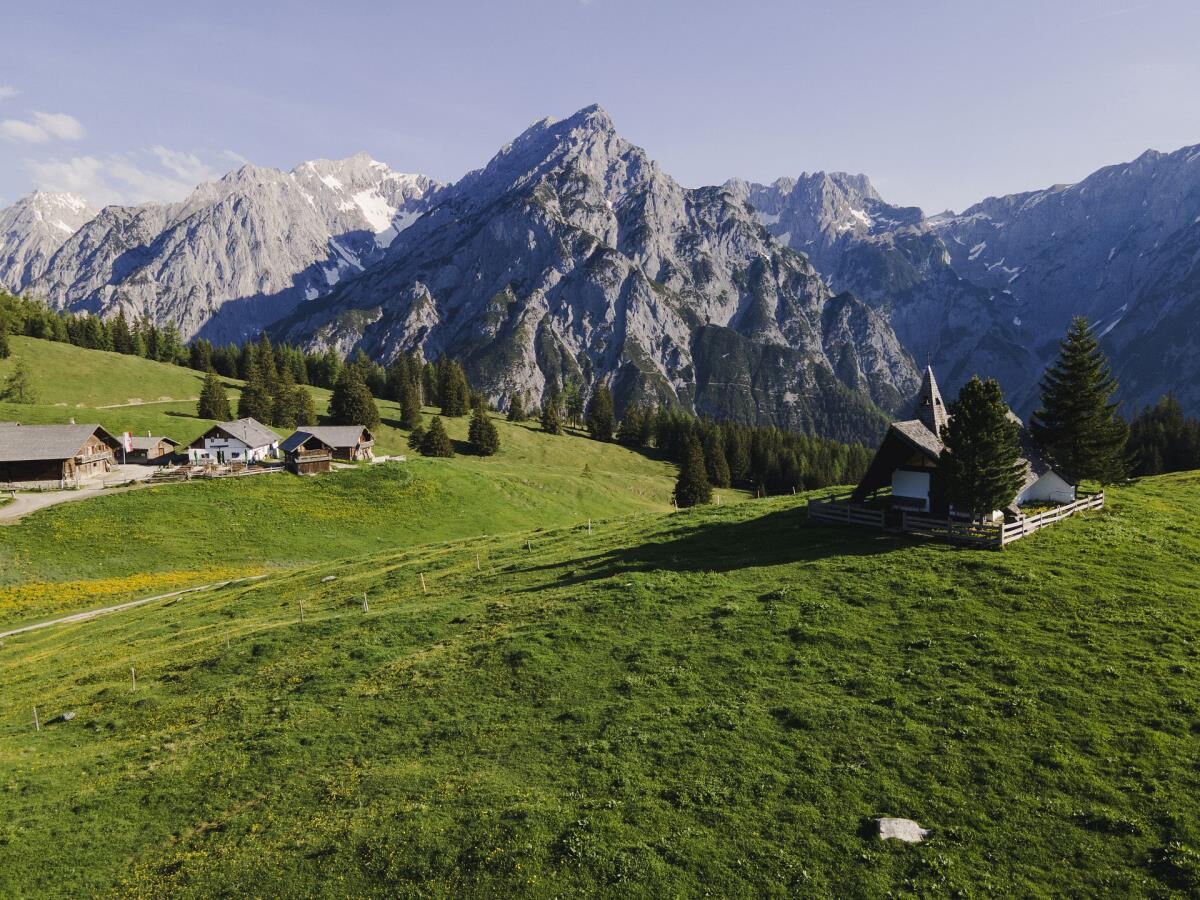 Green alpine meadow with old wooden huts below the rock faces of the Karwendel range, a hiking destination from Gnadenwald in Tyrol