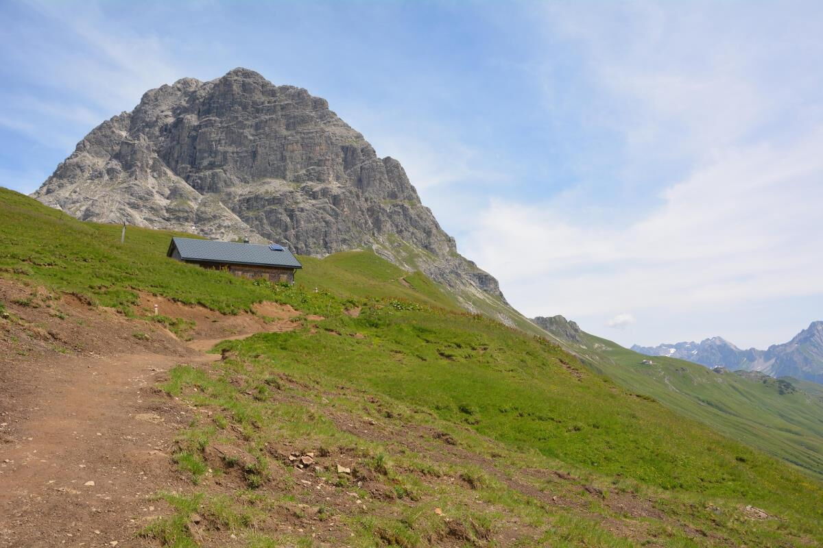 Old alpine hut on a green mountain meadow below the Widderstein in the Kleinwalsertal, a walking destination for families and friends staying at the Sonnenbalkon luxury lodge Bärenkopf