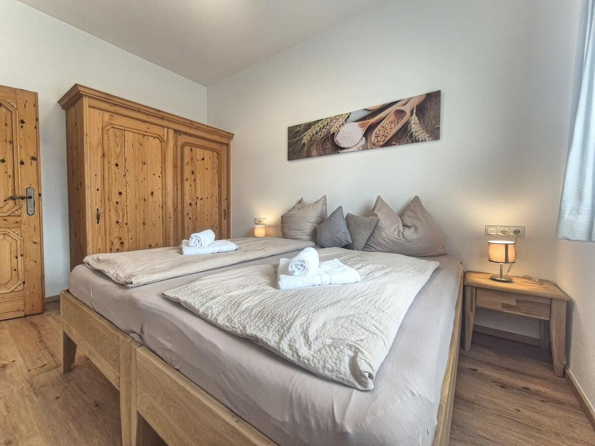 Schlafzimmer in d'Kloane Mühle mit Altholzschrank und Doppelbett, Ferienwohnung am Bauernhof in Tirol