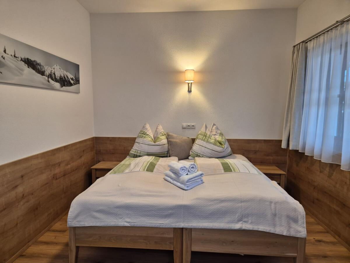 Doppelbett mit Holzverkleidung und Leselampe in der Roggnkammer am Bio-Bauernhof Riedhof in Breitenbach, Ferienwohnung exklusiv für zwei Personen