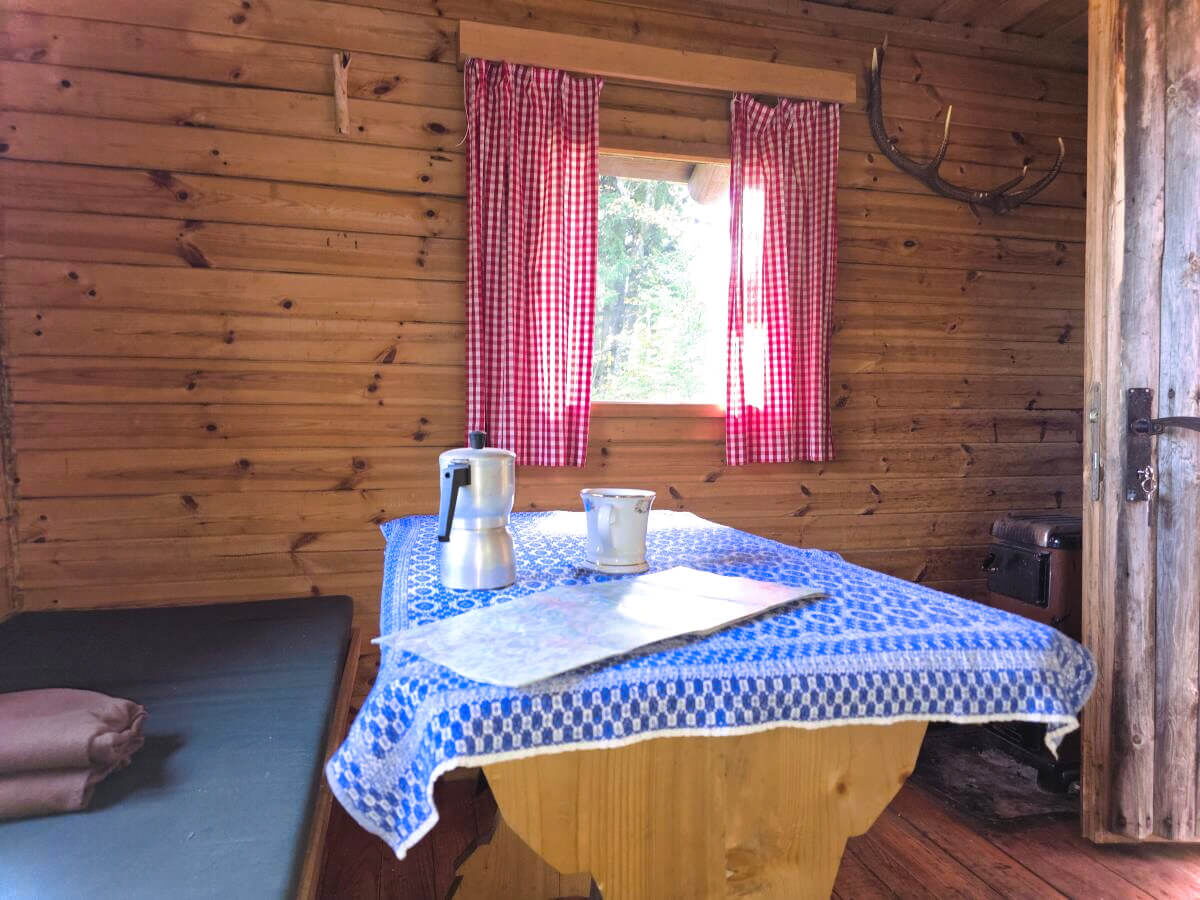 Liebevoll gedeckter Esstisch mit blau-weiß karierter Tischdecke in der Stube der Abenteurer-Hütte mit Wanderkarte für den heutigen Tag.