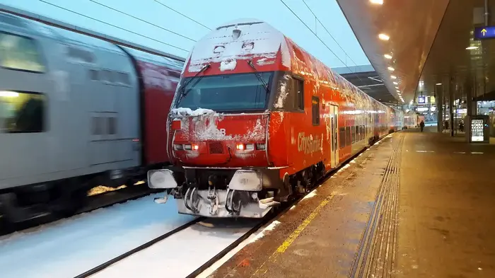 Zug am winterlich verschneiten Bahnsteig, Anreise nach Vorarlberg mit Bahn und Bus