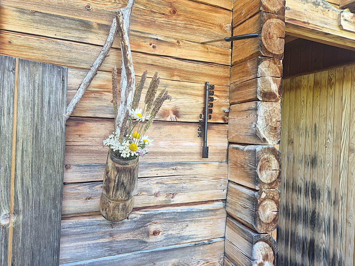 Wiesenblumenstrauß in einem Holzgefäß an der Blockwand der Zarze Almhütte in Osttirol