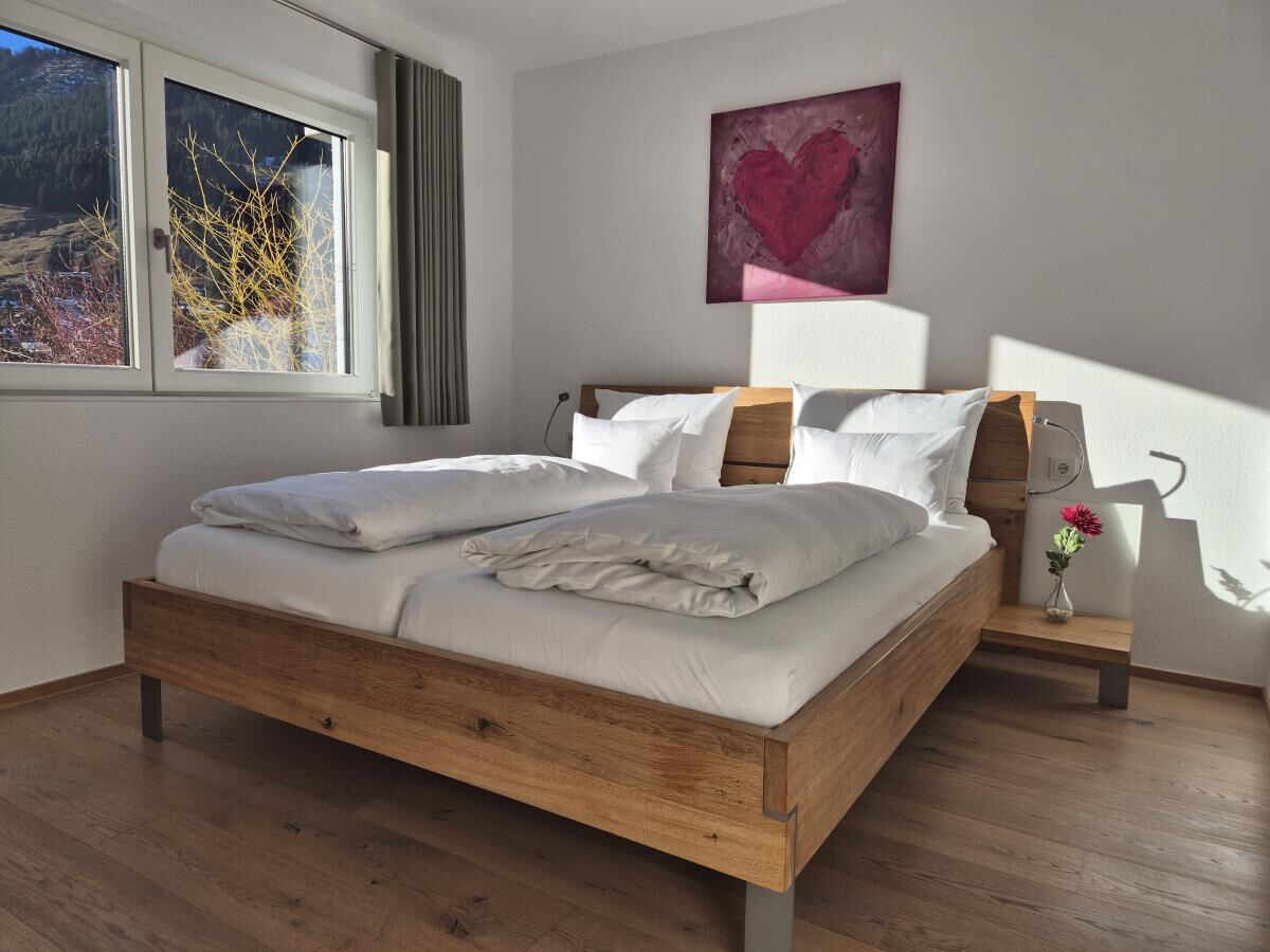 Schlafzimmer mit Massivholz-Doppelbett und Herzbild in der Garten-Luxuslodge Hammerspitze, Luxuslodge für 6 Personen im Kleinwalsertal