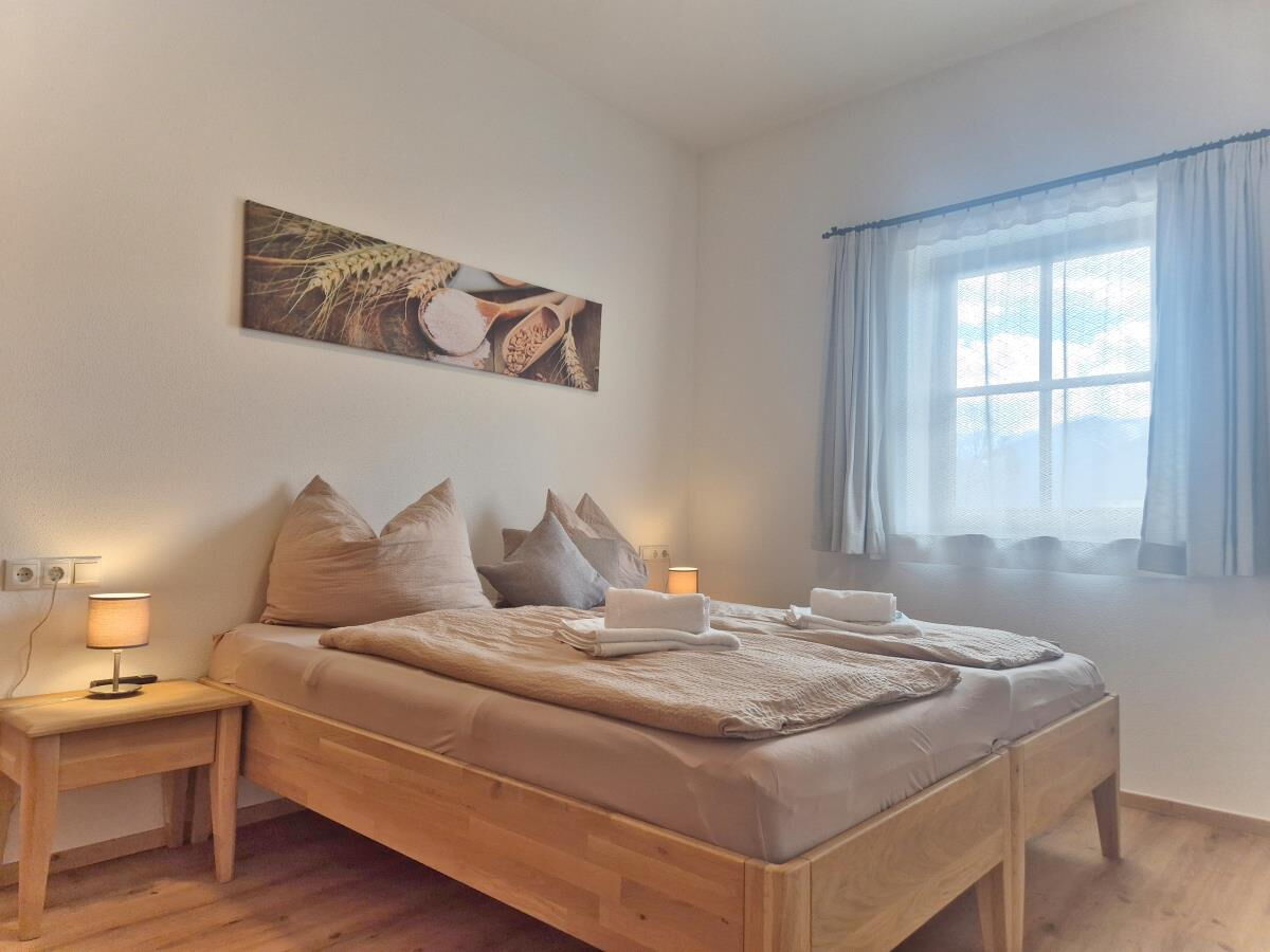 Schlafzimmer in d'Kloane Mühle mit Doppelbett und Bild über dem Bett, Ferienwohnung am Riedhof in Tirol