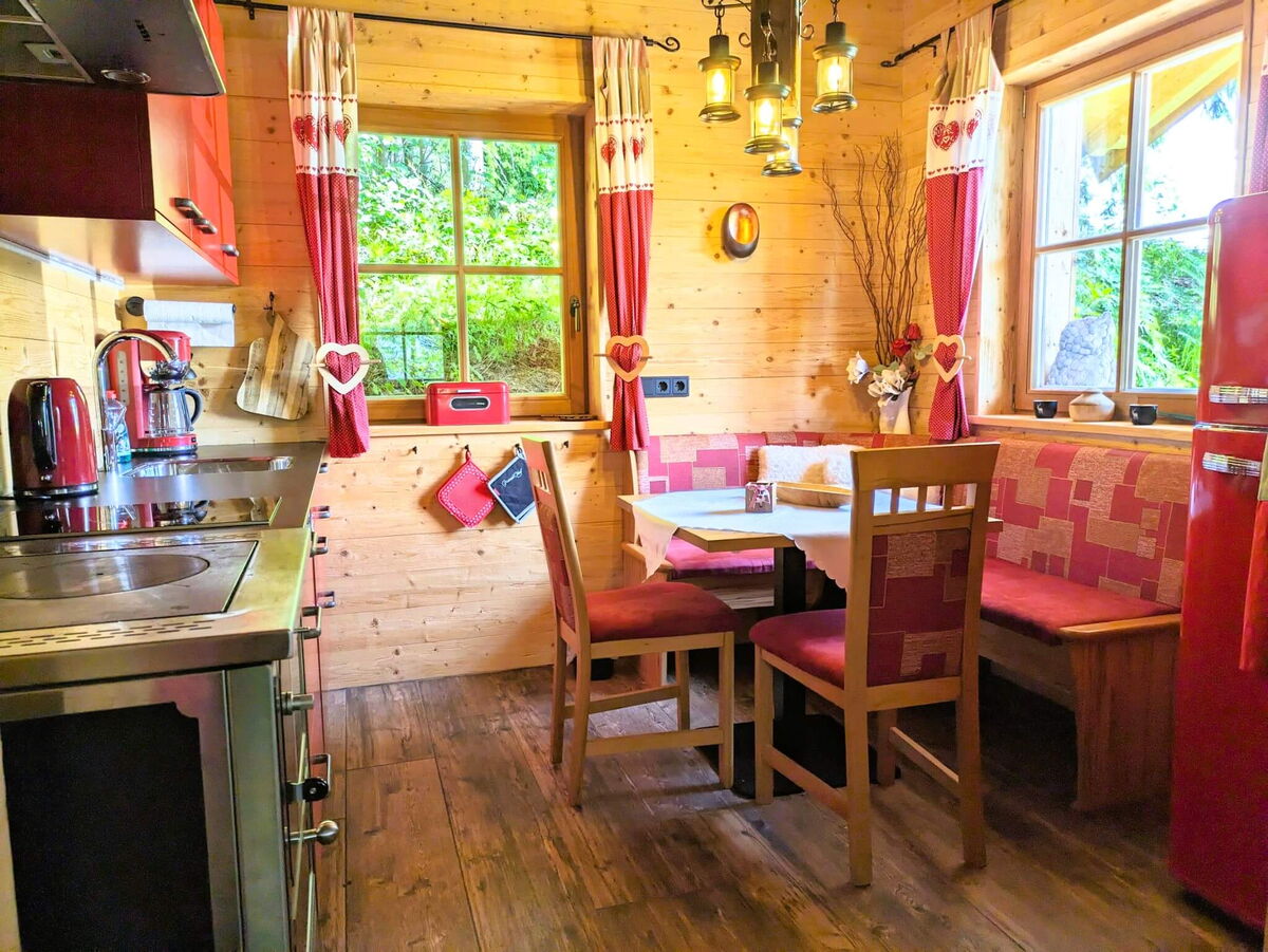 Dining area with a wooden corner bench, laid table and red fridge in the Swiss pine parlour of the Tiroler Hütte near the Karwendel range