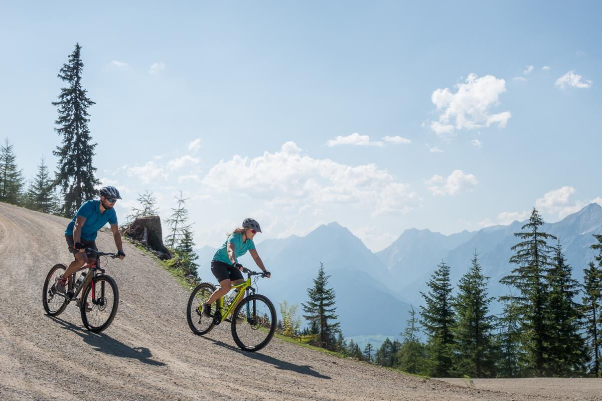 Zwei Mountainbiker auf einem Forstweg über dem Inntal in den Tuxer Alpen, Radtour ab der Ferienwohnung Sternenhimmel am Kolsassberg