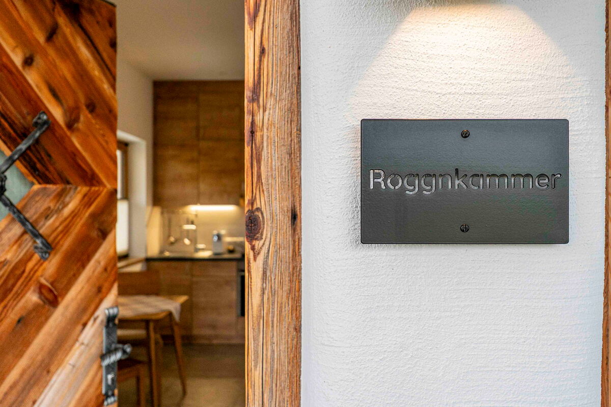 Das Schild Roggnkammer neben der alten Holztür am eigenen Eingang der Ferienwohnung am Riedhof in Breitenbach in Tirol