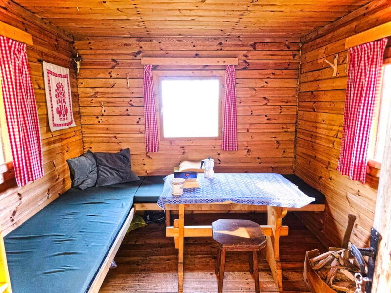 Innenraum der Abenteurer-Hütte mit Holzbank, Esstisch und Sitzecke aus Massivholz