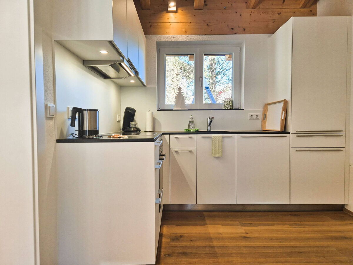 Fully equipped kitchen with oven, coffee machine and a window under the sloping roof in the Panorama luxury lodge Ifen in the Kleinwalsertal