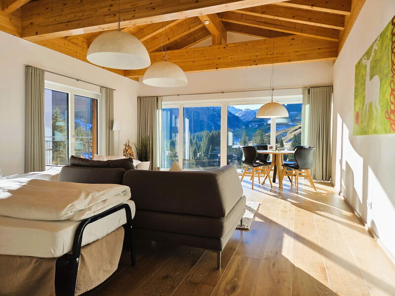 Offener Wohn- und Schlafbereich unter dem Dachstuhl mit Fensterfront in der Panorama-Luxuslodge Ifen im Kleinwalsertal
