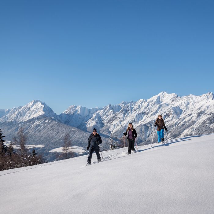 Durch die verschneite Winterlandschaft mit den Schneeschuhen wandern.