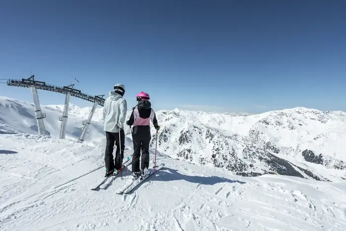 Two skiers in the Hochzillertal-Hochfügen ski area looking out over snow-covered mountains