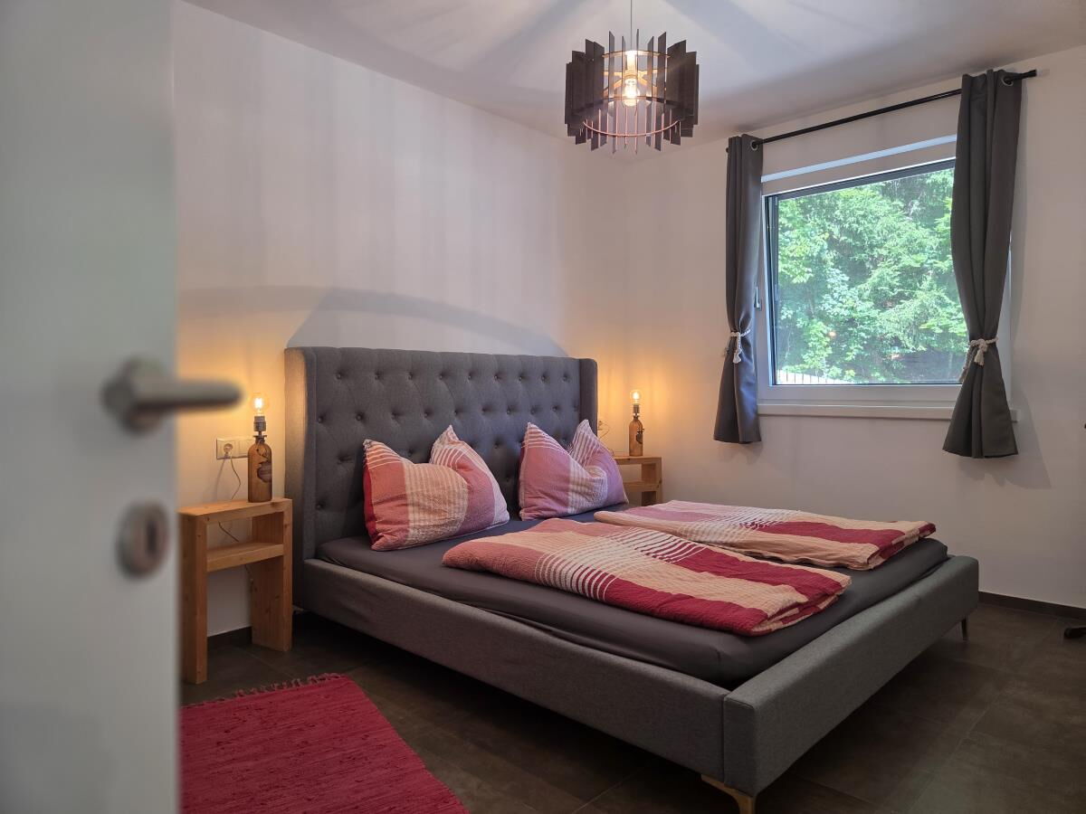 Schlafzimmer mit Doppelbett und gepolstertem Kopfteil in der Pferdeheimat am Karwendel in Gnadenwald, Ferienwohnung für zwei bis drei Personen