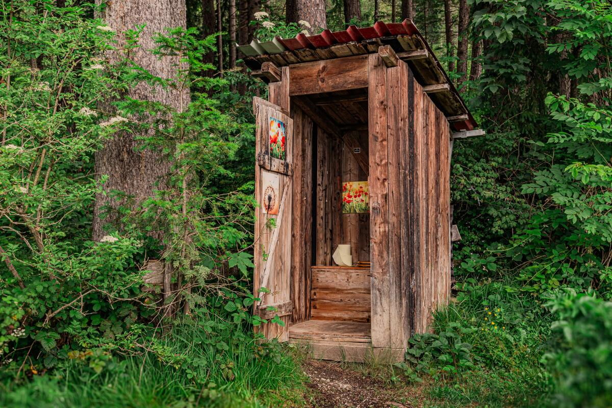 Hölzernes Plumpsklo am Waldhüttl in Terfens, traditionelles Außen-WC im Wald, einfache Hüttenausstattung.