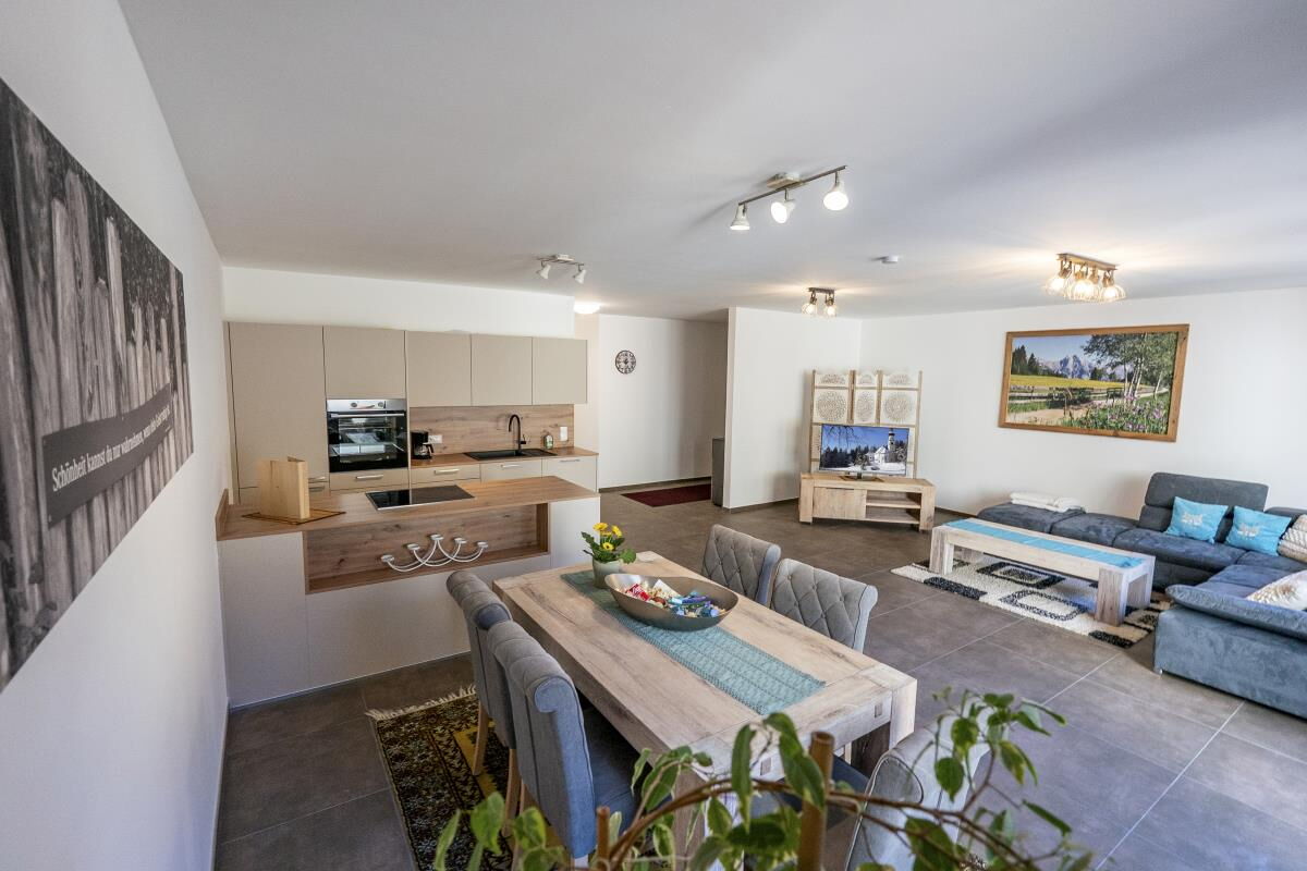 View through the open living room with dining table to the kitchen in the Alpenfamilienglück in Gnadenwald, 80 square metres at the horse farm in Tyrol