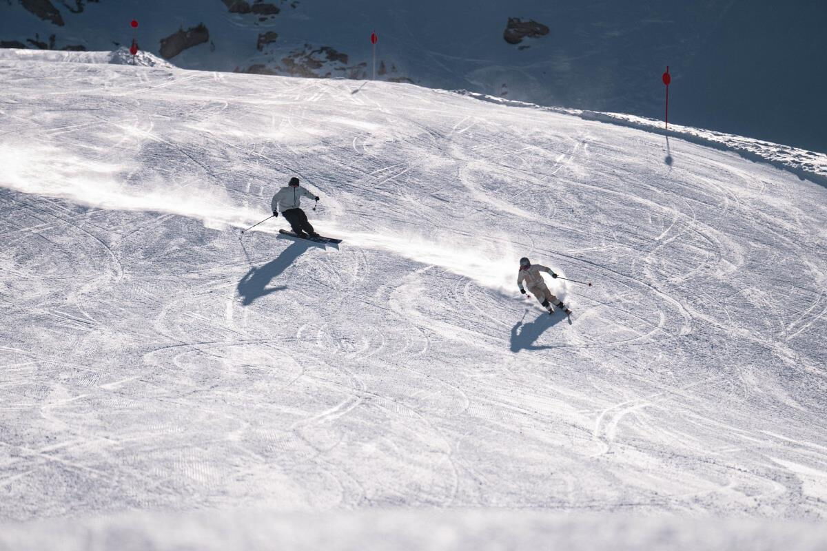 Two skiers carving turns on the sunny slope, family ski holiday near the Waldsicht am Karwendelgebirge holiday apartment in Gnadenwald