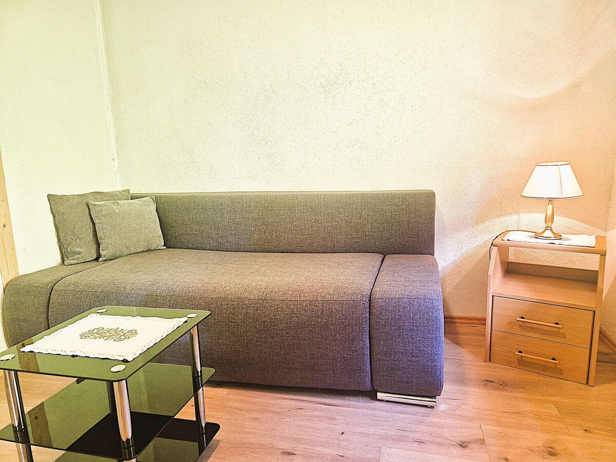 Graue Couch mit Beistelltisch und Leselampe im Wohnbereich des Kochhäusls am Wattenberg, gemütlicher Rückzugsort in der Berghütte