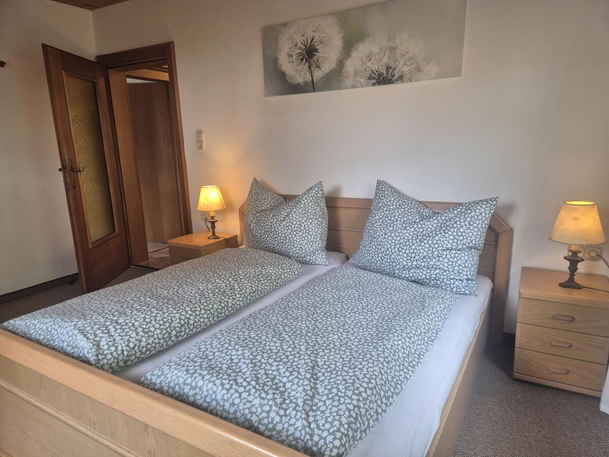 Blick von der Tür in das Schlafzimmer der Ferienwohnung Sonnseitn Karwendel mit Doppelbett und zwei Nachtkästchen