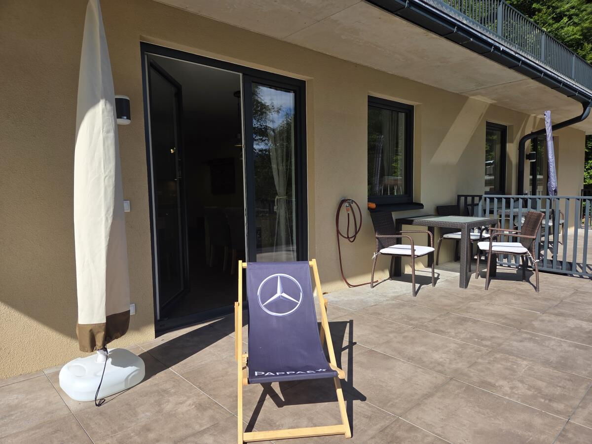 Terrace of the Waldsicht holiday apartment with deck chair, table, chairs and parasol in front of the terrace door