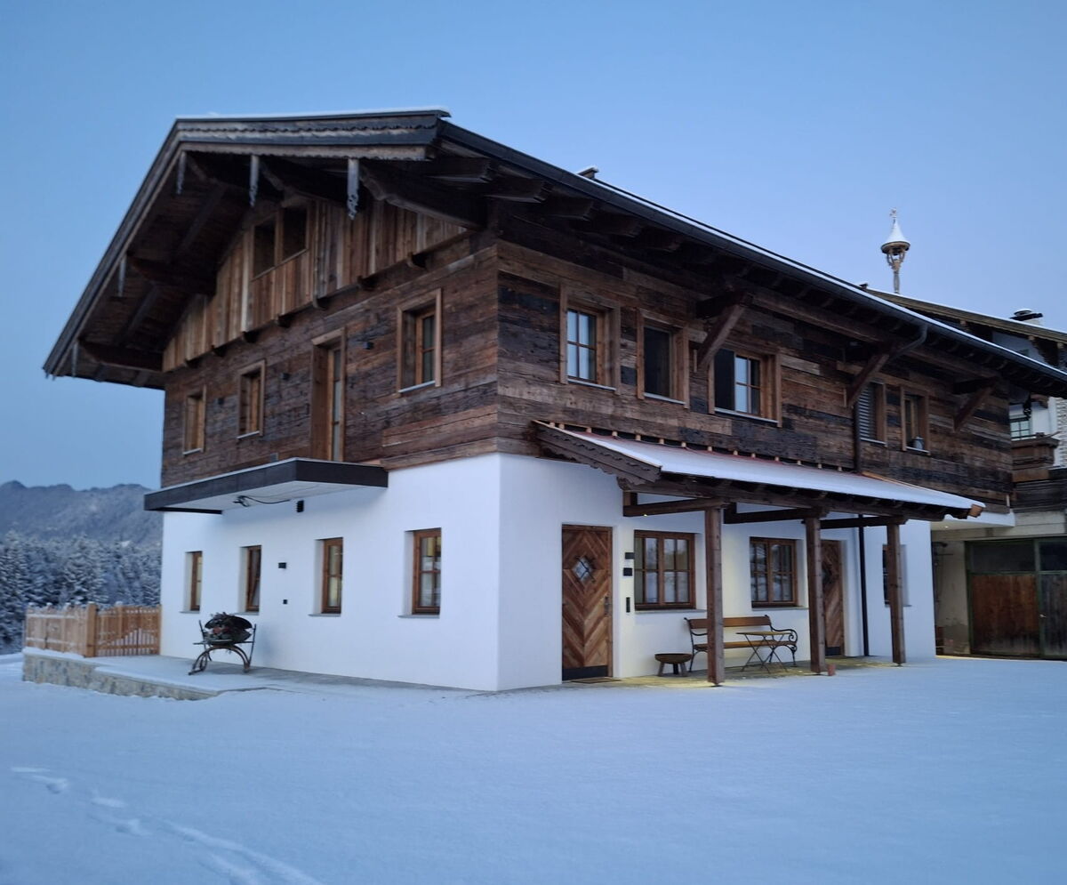 Das Riedhof-Zuahaus in Breitenbach unter Schnee mit Holzfassade und Vordach, Ferienwohnungen am Bio-Bauernhof in Tirol im Winter