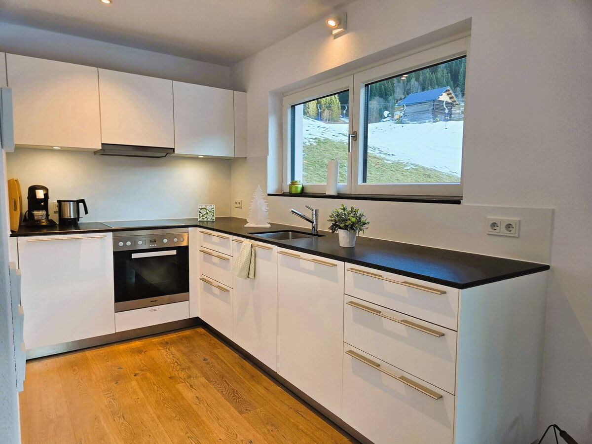 Voll ausgestattete Küche in L-Form mit Backofen, Geschirrspüler und Fenster in der Bergwiese-Luxuslodge Zwölferkopf, Luxuslodge für 6 Personen im Kleinwalsertal