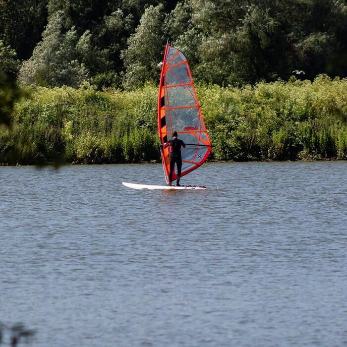 Erste Versuche beim Windsurfen am großen See.