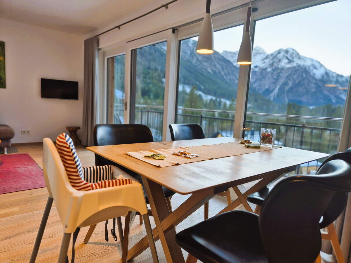 Large dining table for six in front of the panorama window with mountain view in the Alpenglück luxury lodge Widderstein, holiday apartment for families and friends in the Kleinwalsertal